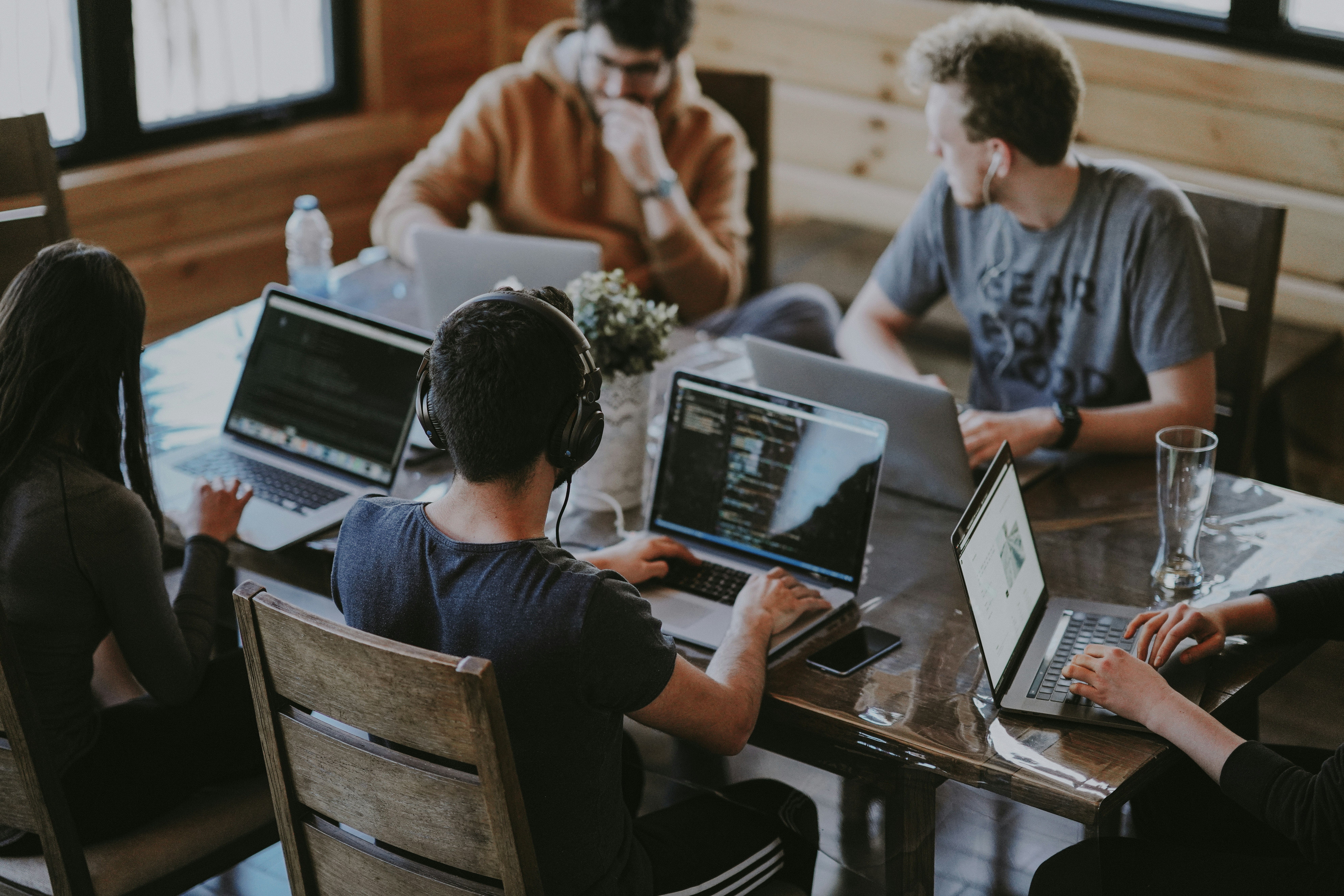 group of people working together at a table all on their laptops